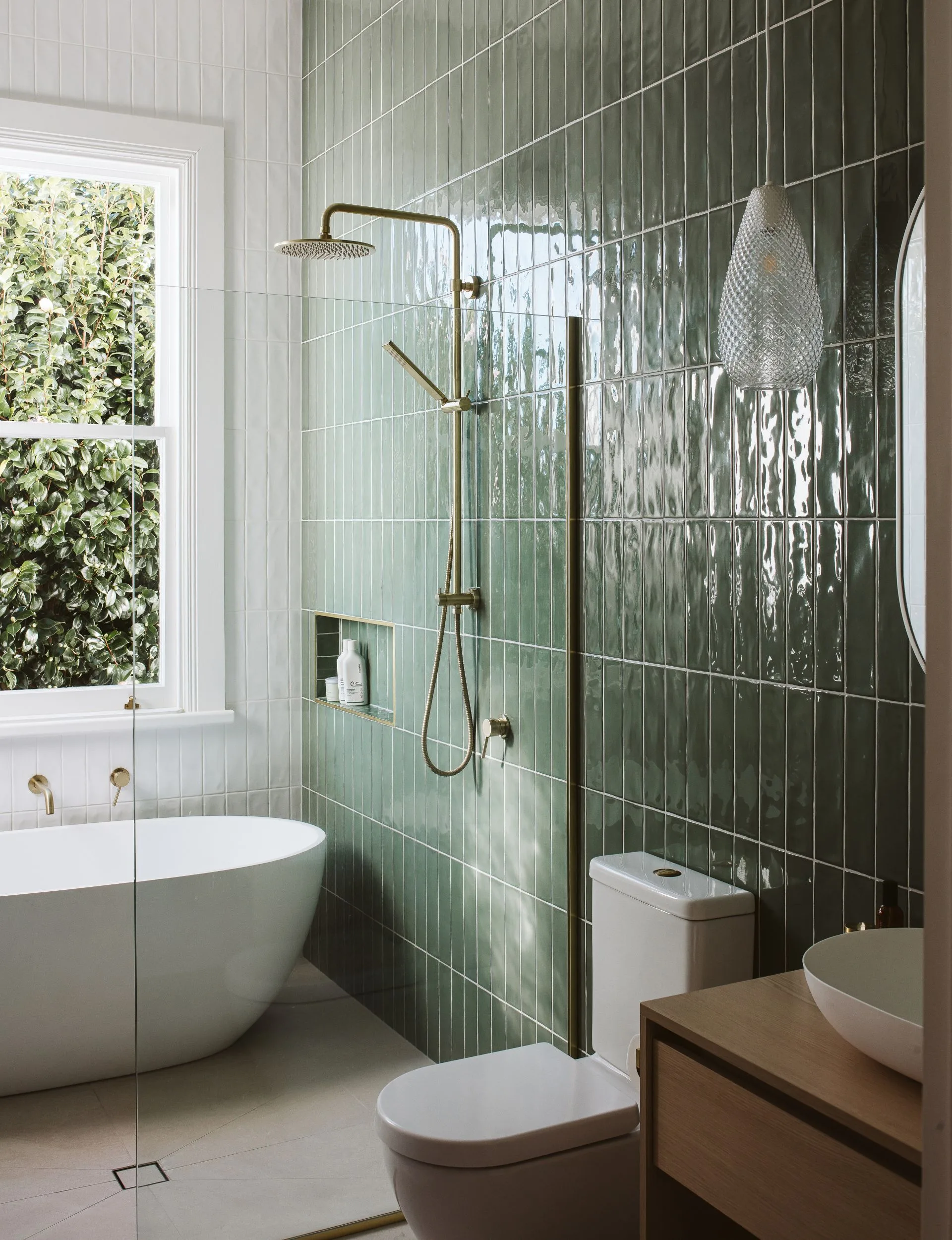 La salle de bain dispose d'une baignoire ovale blanche avec un mur de carrelage vert foncé.