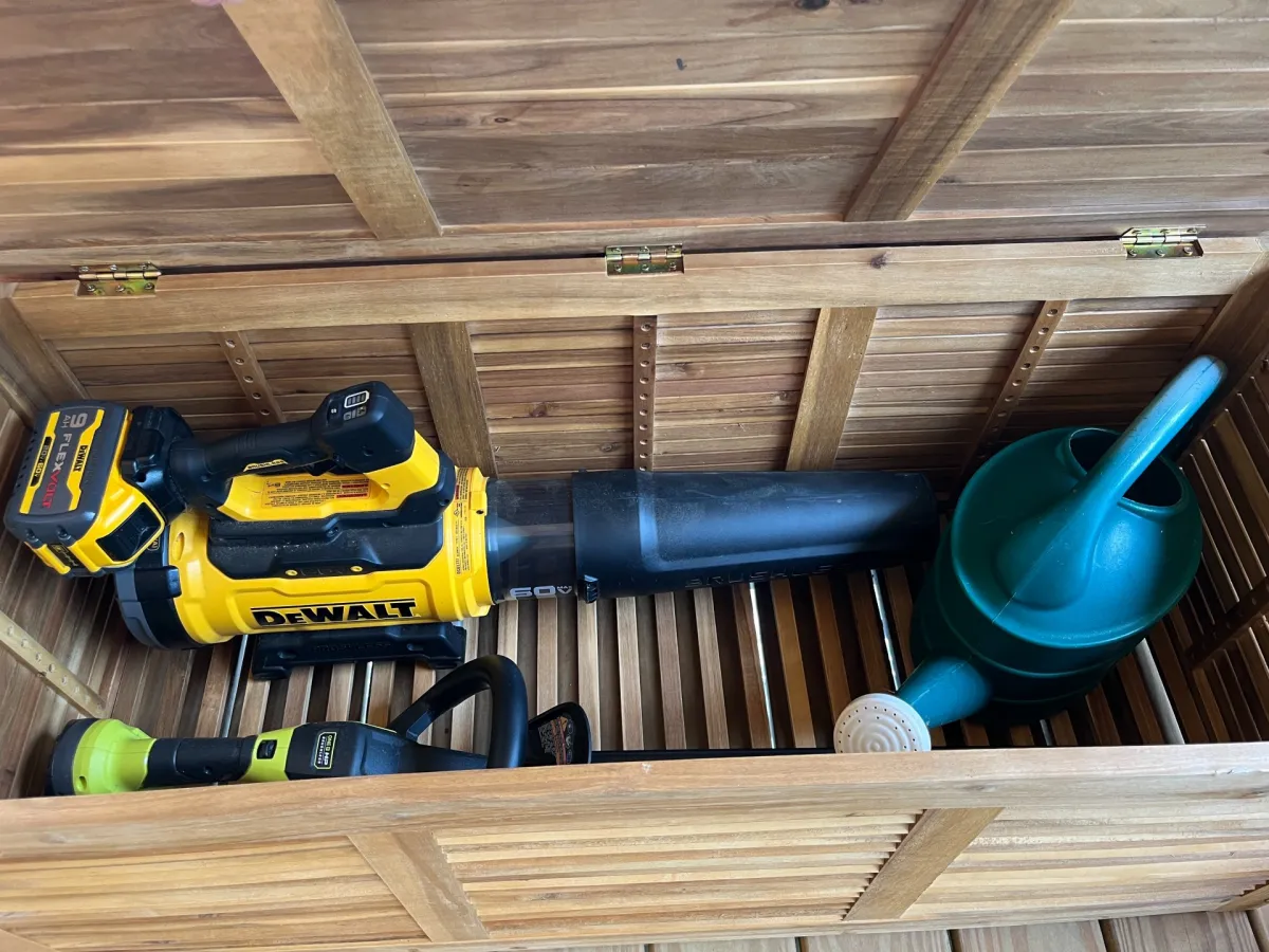 The Tangkula 48-Gallon Acacia Wood Deck Box open to show it full of yard care tools during testing 