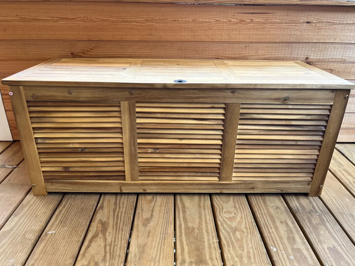 The Tangkula 48-Gallon Acacia Wood Deck Box on a wooden deck during testing