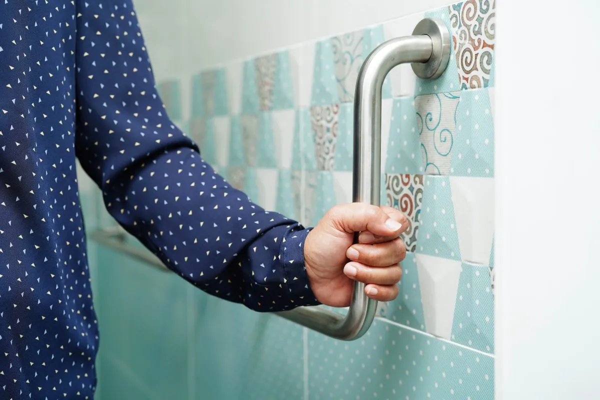 Woman holds on to grab bar in bathroom.