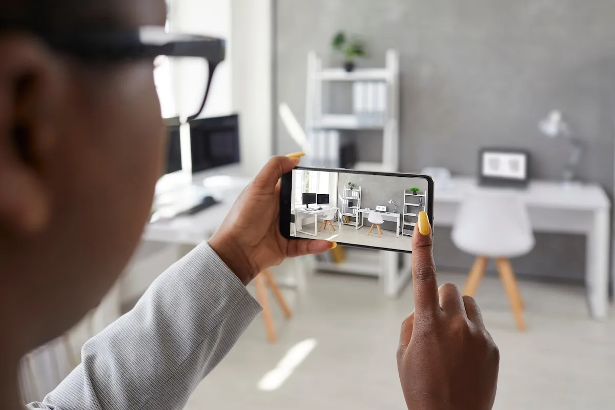 Black designer taking office interior photos, making presentation or video calling client using smart phone app.