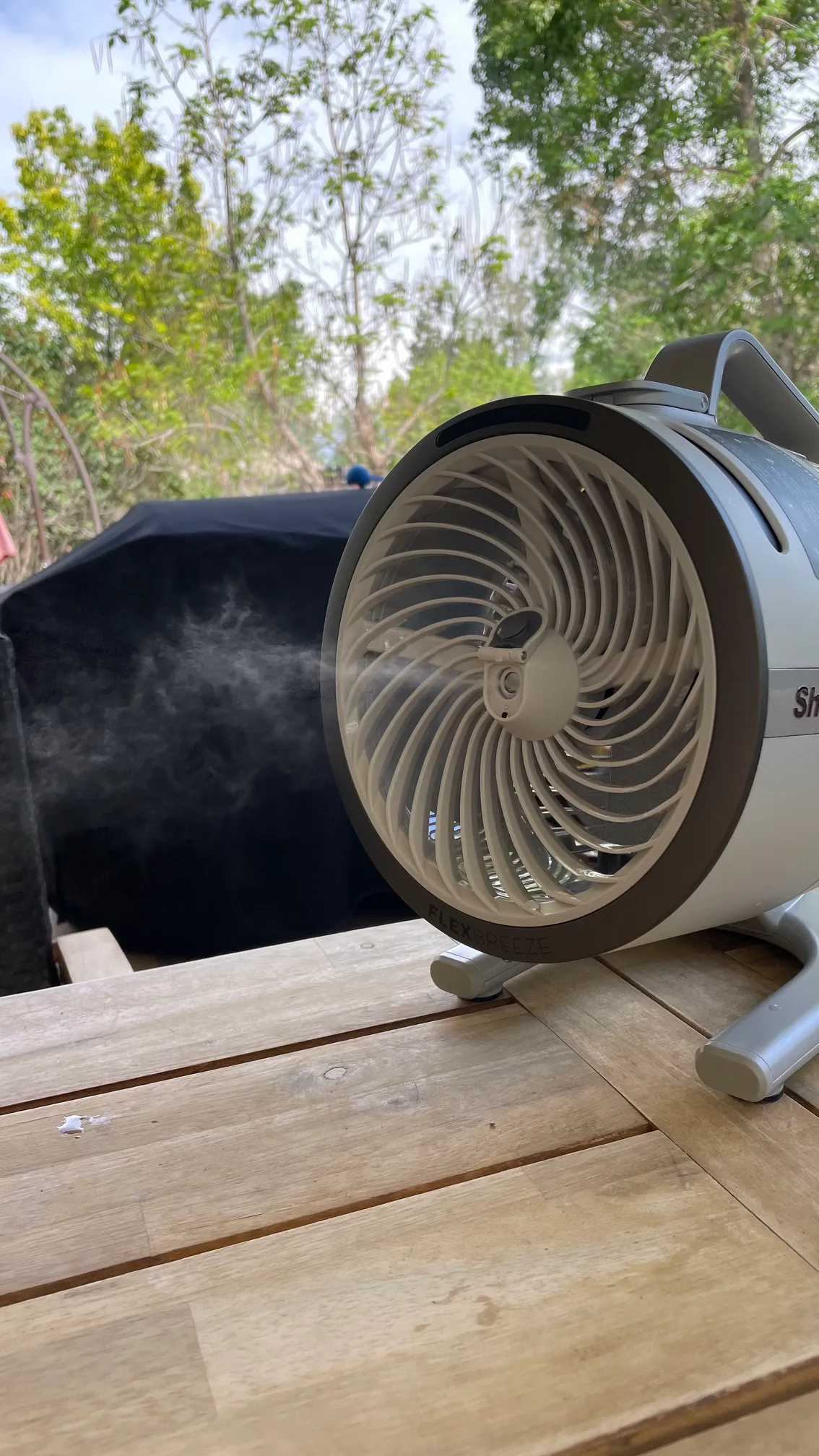 The mister on the Shark FlexBreeze HydroGo-Pro Fan shooting a fine mist over an outdoor table