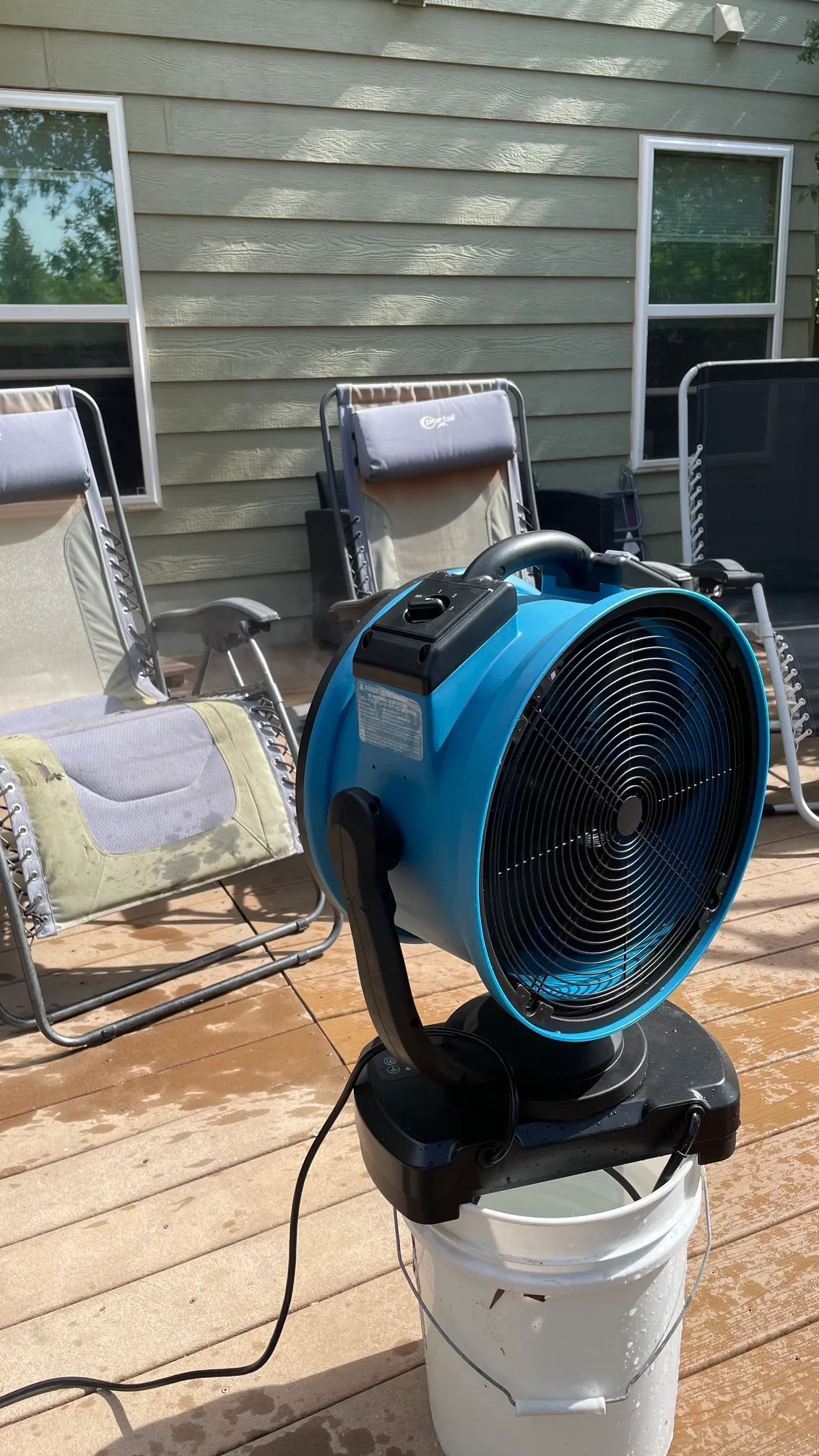 The XPower FM-88W misting fan cooling a three gravity chairs on a deck during testing