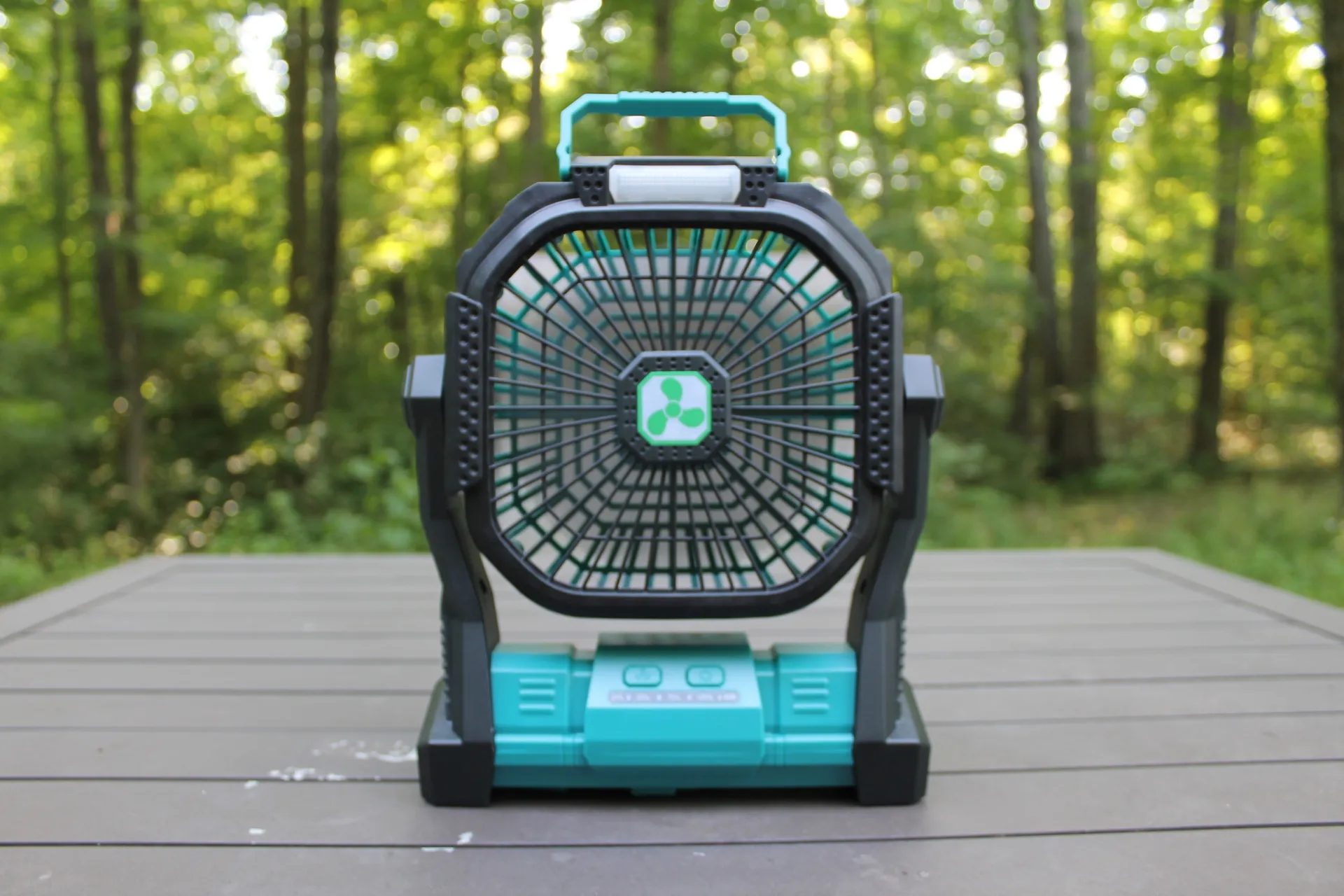 OnlyNew Portable Fan Powered on gray deck in front of forest