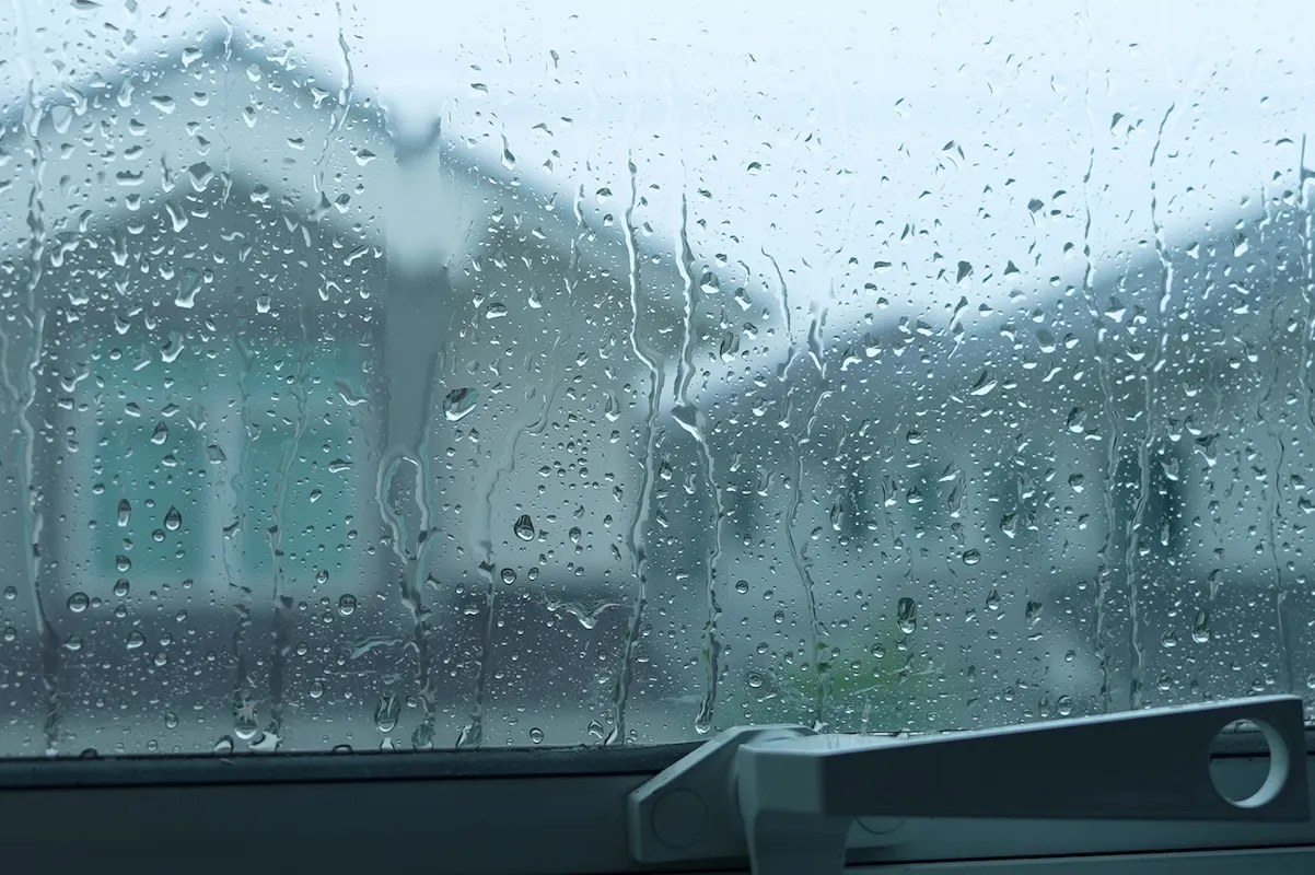 View through a window of a house across the street in stormy, rainy weather.
