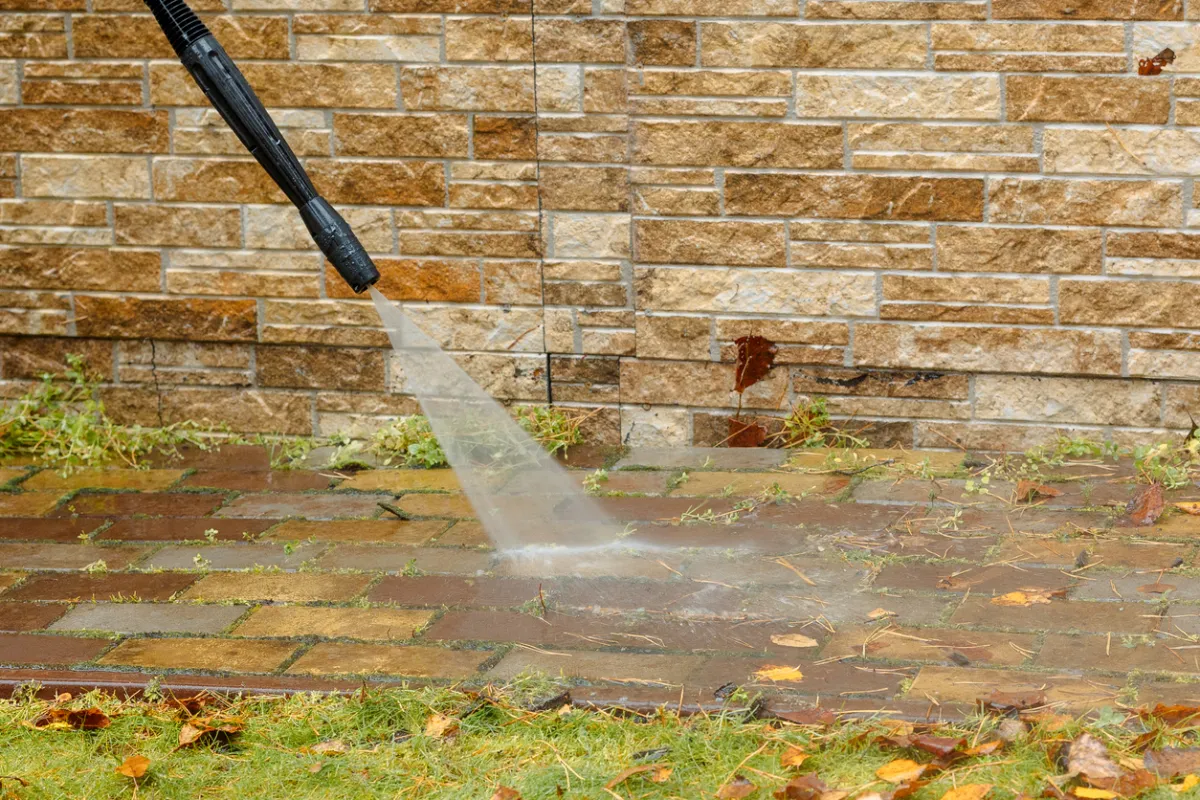 Power washer cleans bricks outside.
