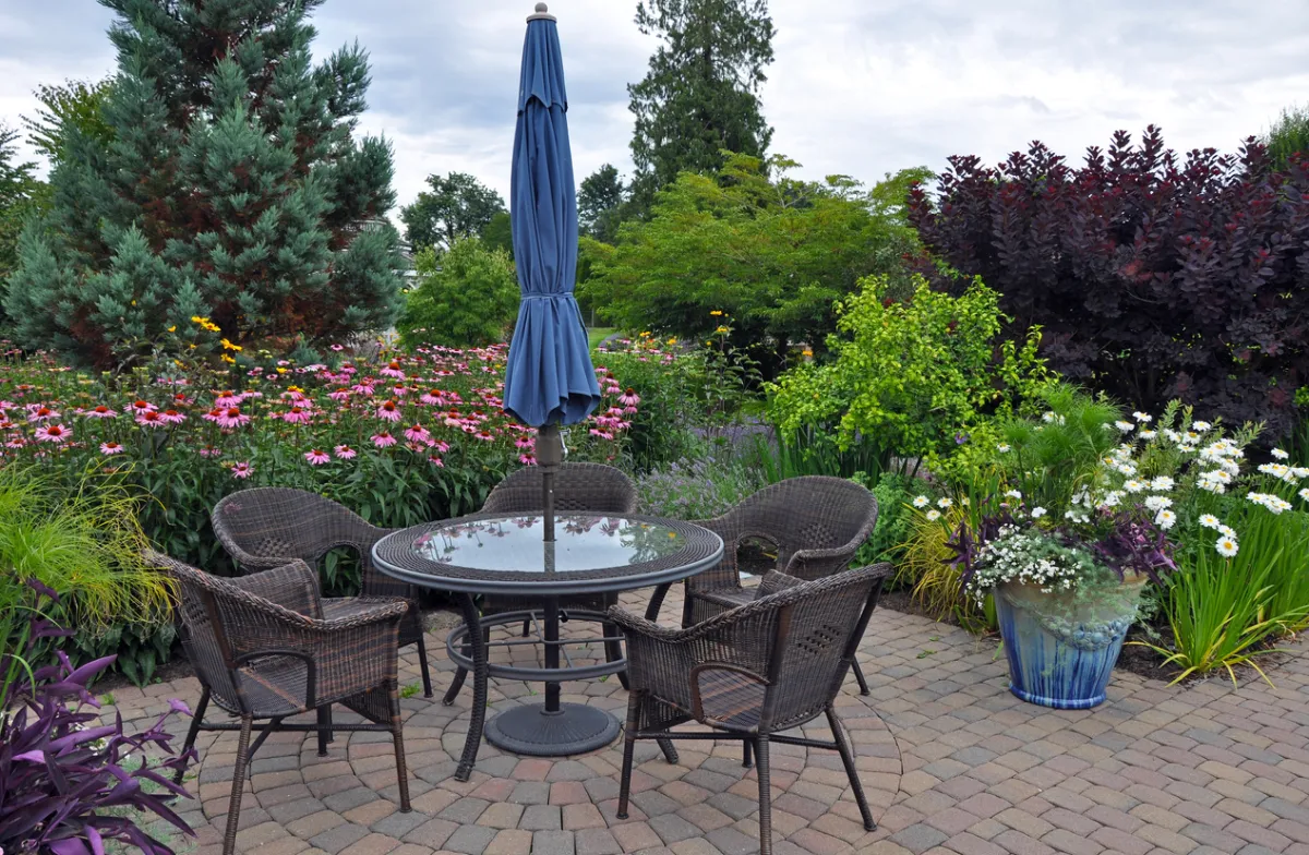 Garden patio with table and four patio chairs and umbrella.