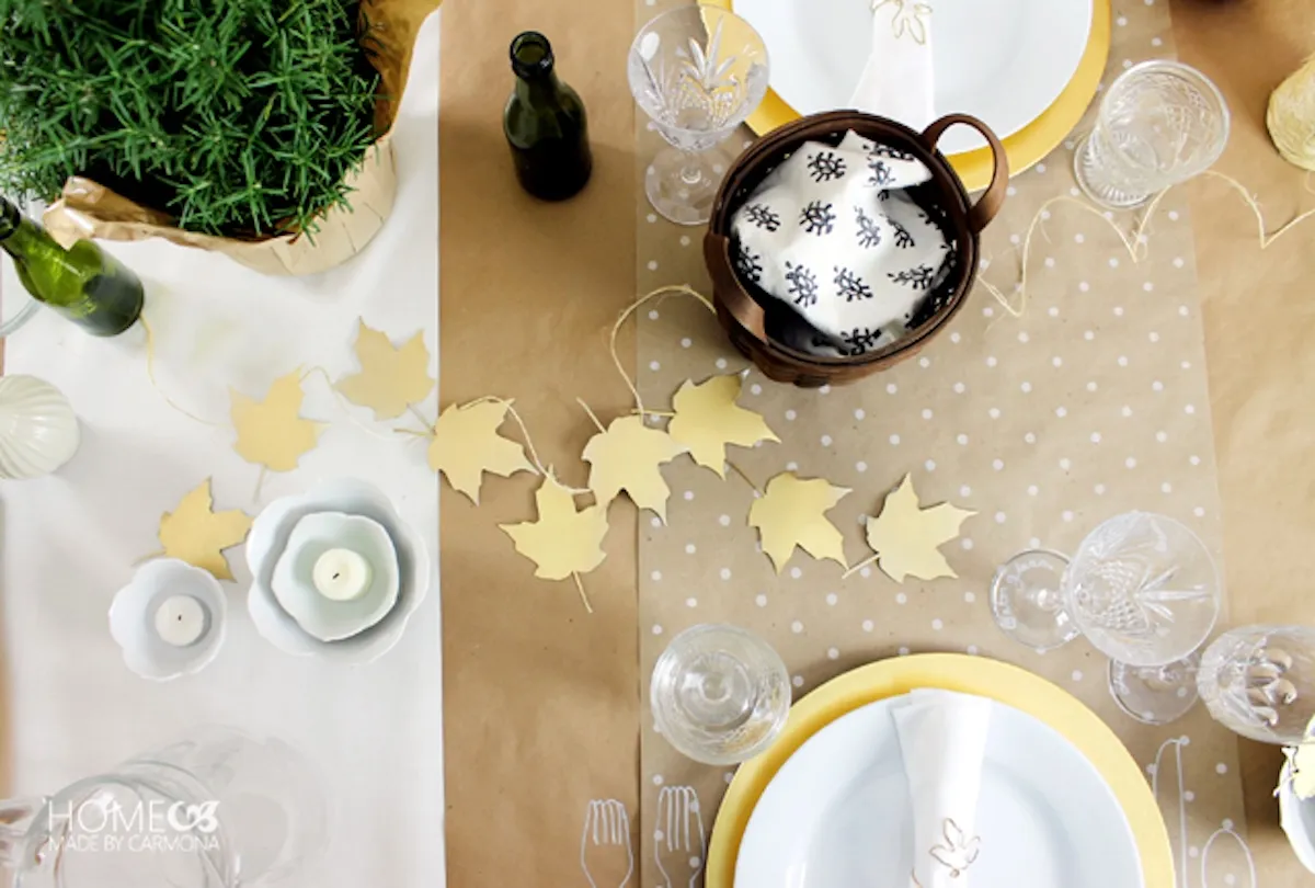 Birds eye view of a dining table with gold fall leaves and other fall decor.