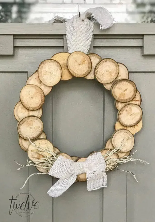 A DIY wreath made of wood  circles hangs from a front door.
