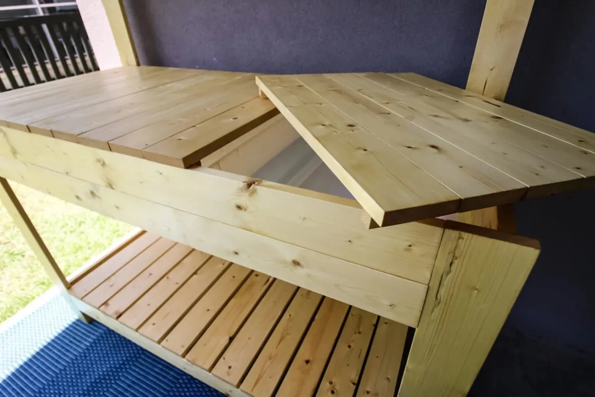 Wood slatted potting bench with a removable counter panel that reveals hidden storage underneath.