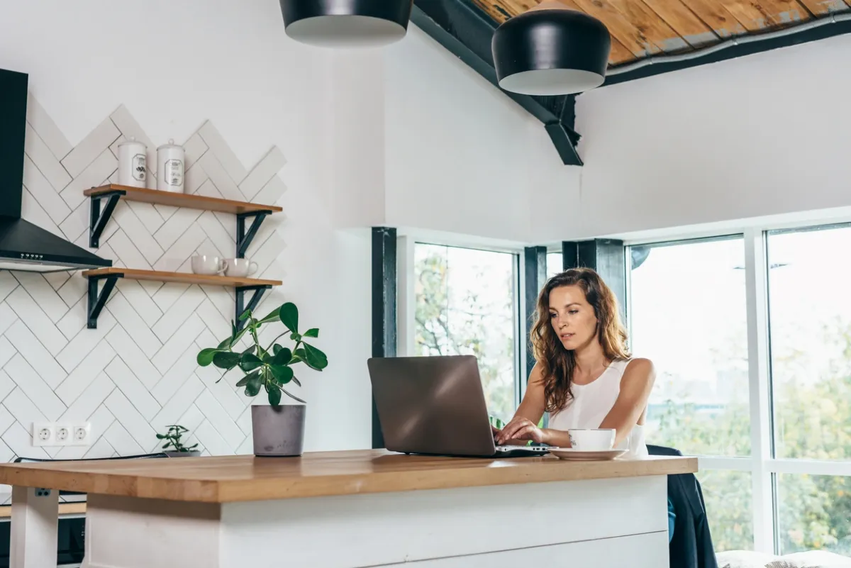 Woman working at a laptop at a kitchen island.