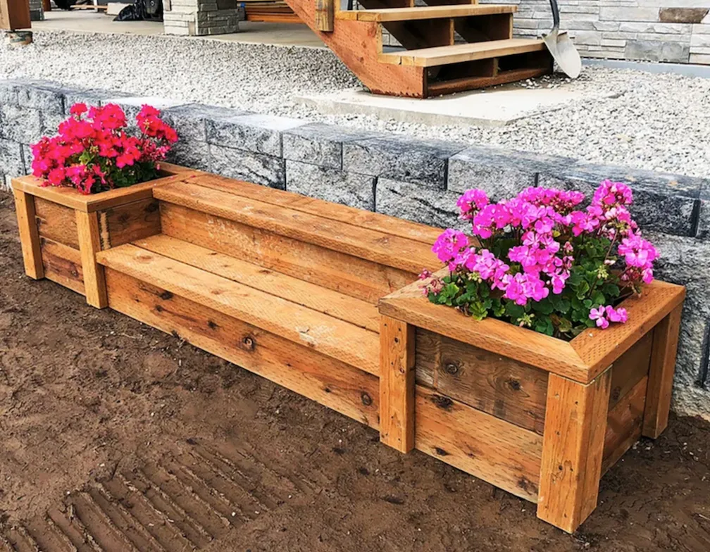 wooden bench in backyard landscaping flanked by two built in planter boxes with flowers