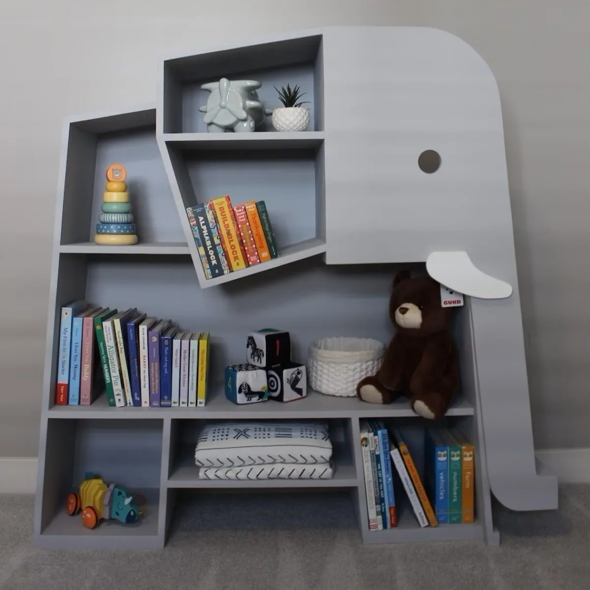 Grey elephant shaped bookshelf filled with children's books.