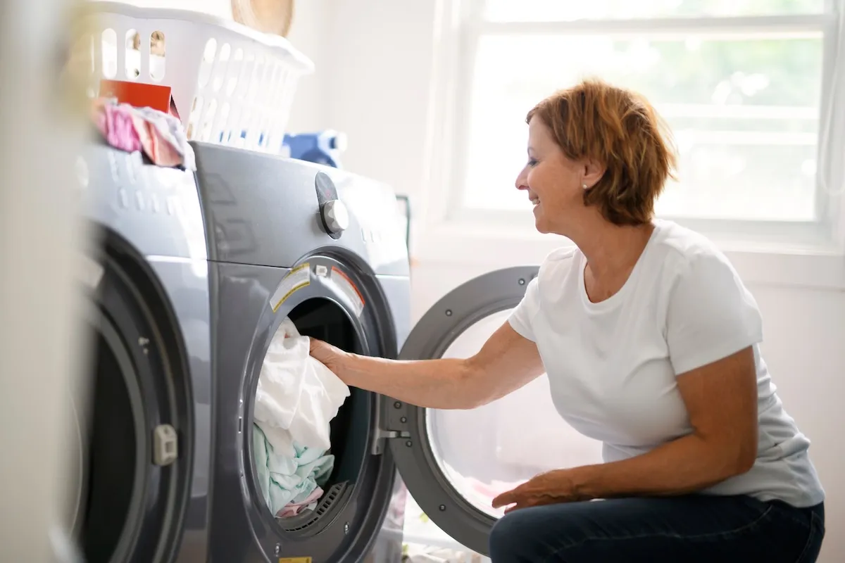 A woman loads a washing machine.