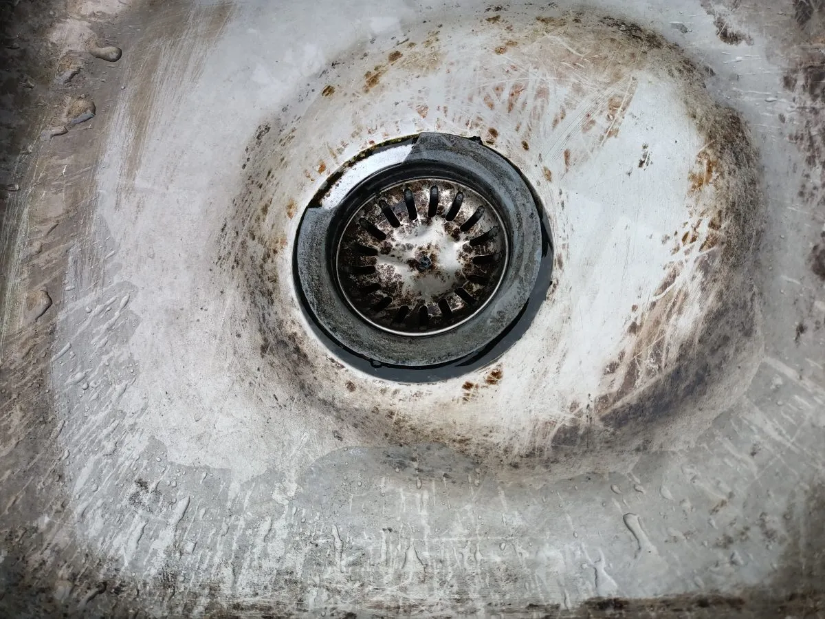 Close-up of a dirty, rusty stainless steel kitchen with stains and scratches