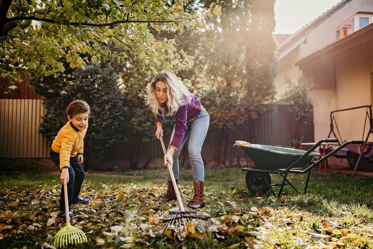 Mother and son raking leaves together.