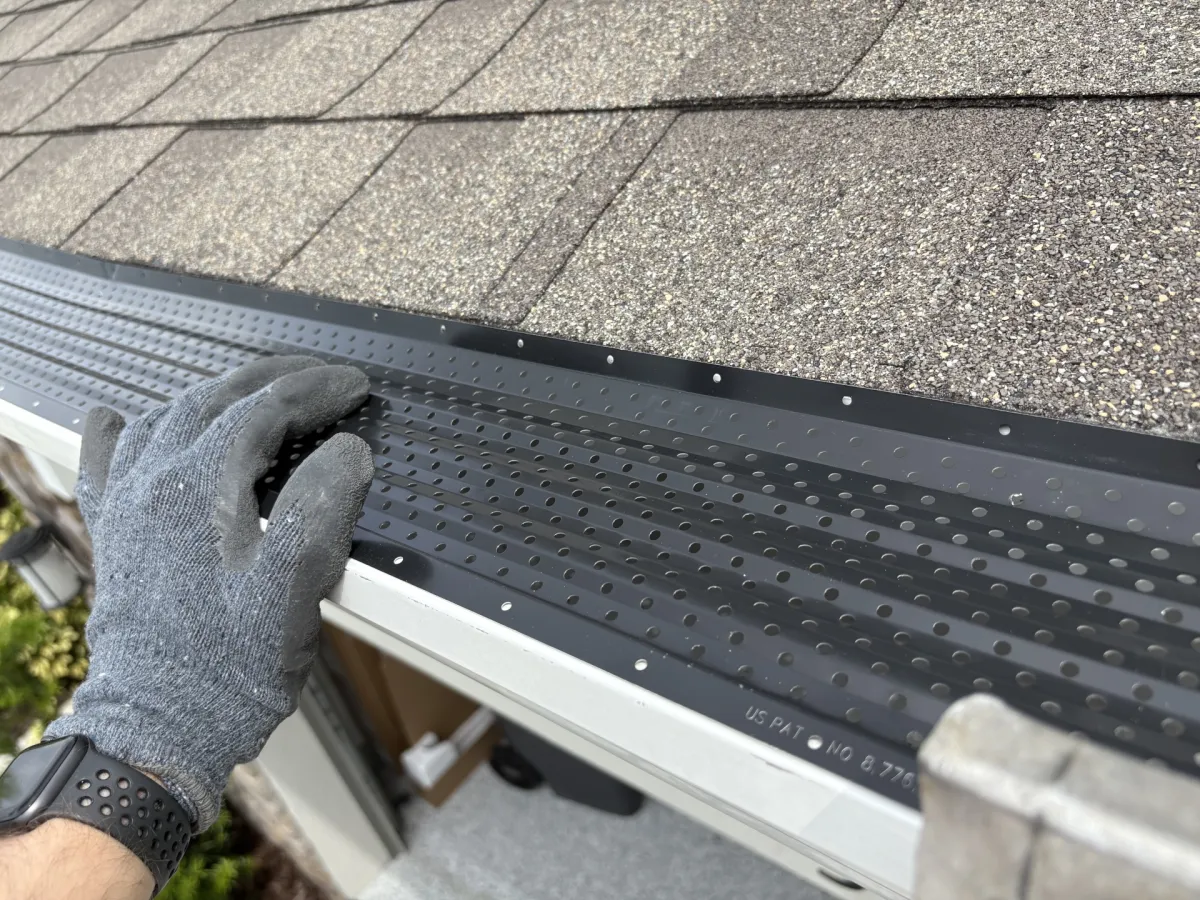 Person installing black LeafTek Gutter Guard