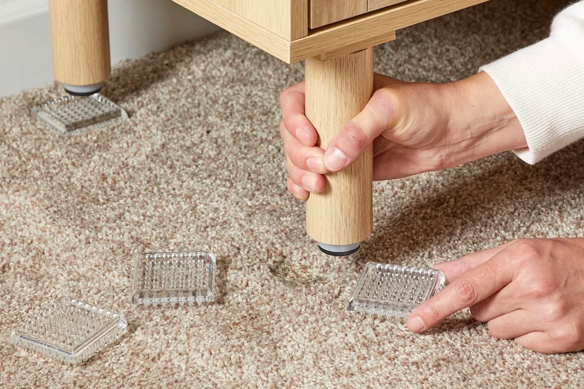 Person uses carpet protectors to put under a table to prevent dents in carpet.