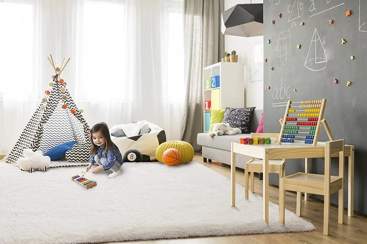 Child in modern, upscale playroom with a fuzzy white rug, tipi, and scattered toys.