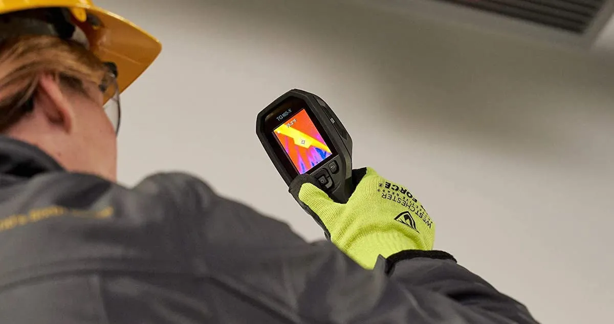 Rear view of a worker holding a thermal camera.