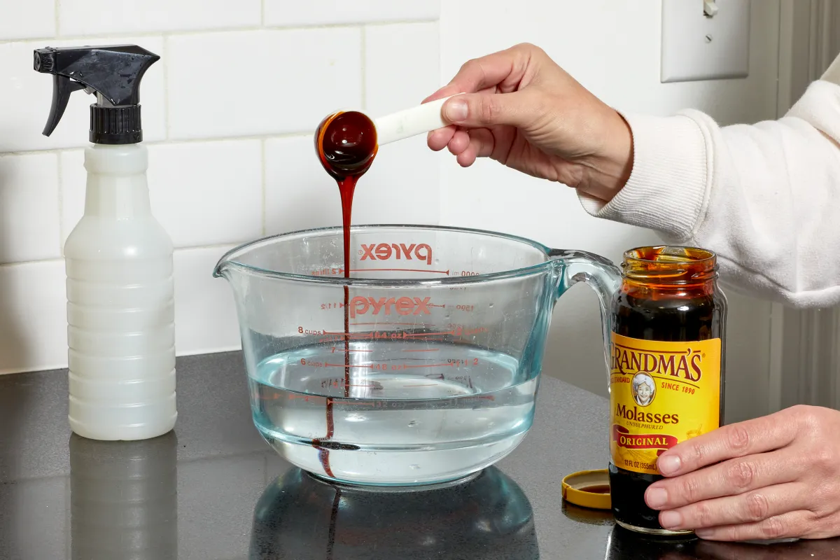 Woman spoons molasses into a measuring cup with water.