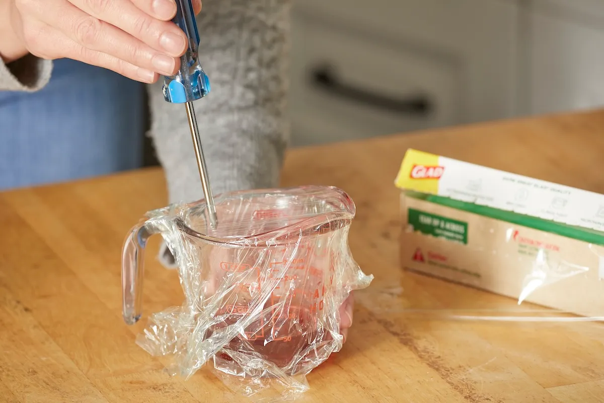 You can have your bananas and eat them, too, without fighting off fruit flies in your kitchen. Craft a simple homemade trap by pouring apple cider vinegar and a squirt of liquid dish soap in a cup or small dish. Cover the container with plastic wrap and poke a few small holes in the top so you can lure the flies in without their being able to slip back out.