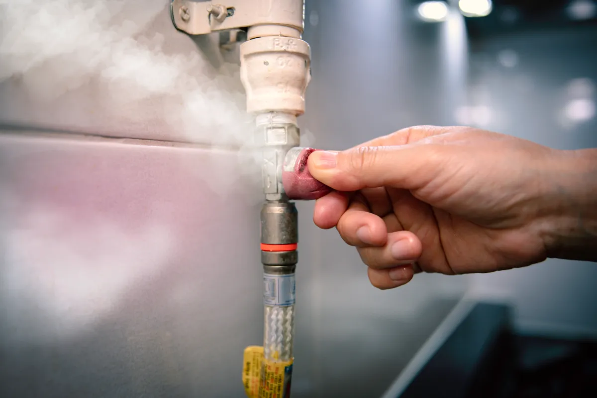 Person releasing steam from a pipe by twisting the valve.