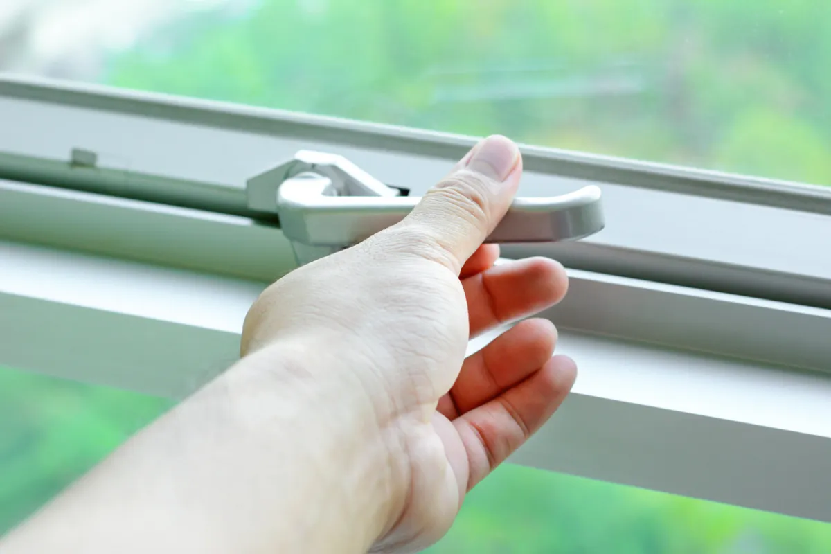 Woman securing the lock on a home's window.