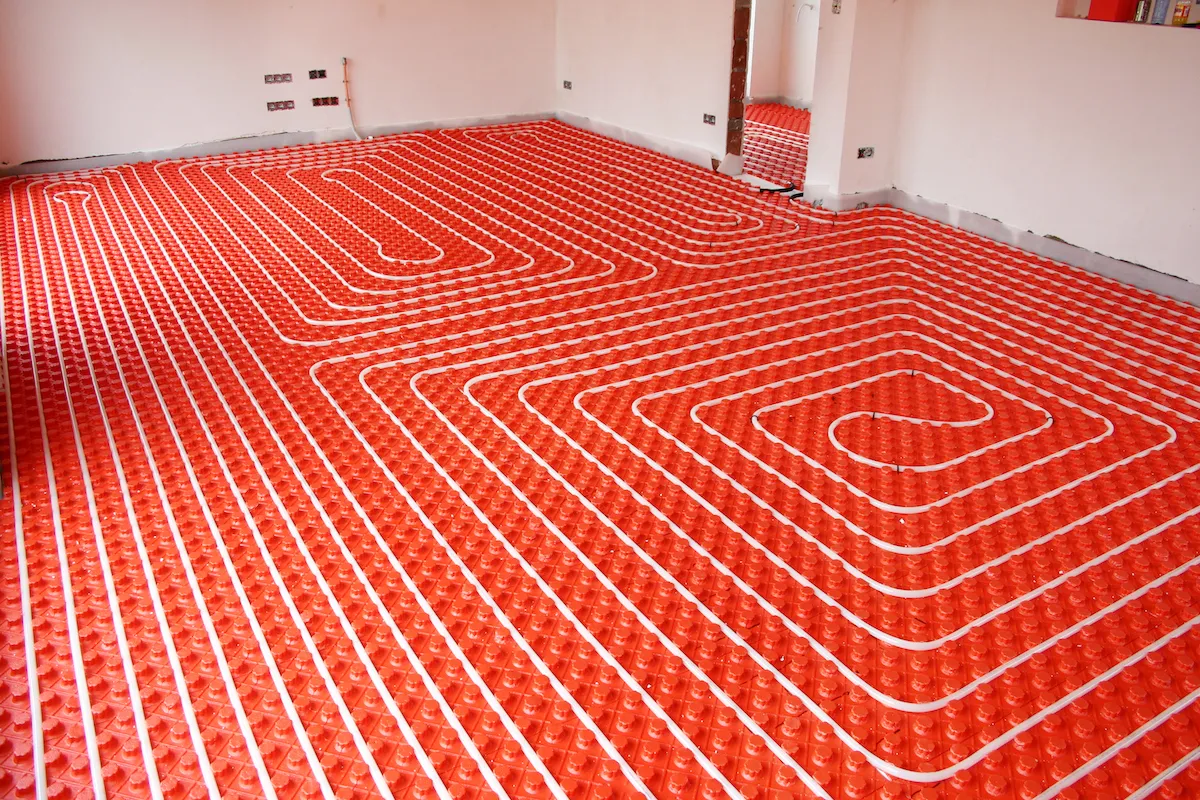 Radiant floor heating system with a red base and paths of piping over top.