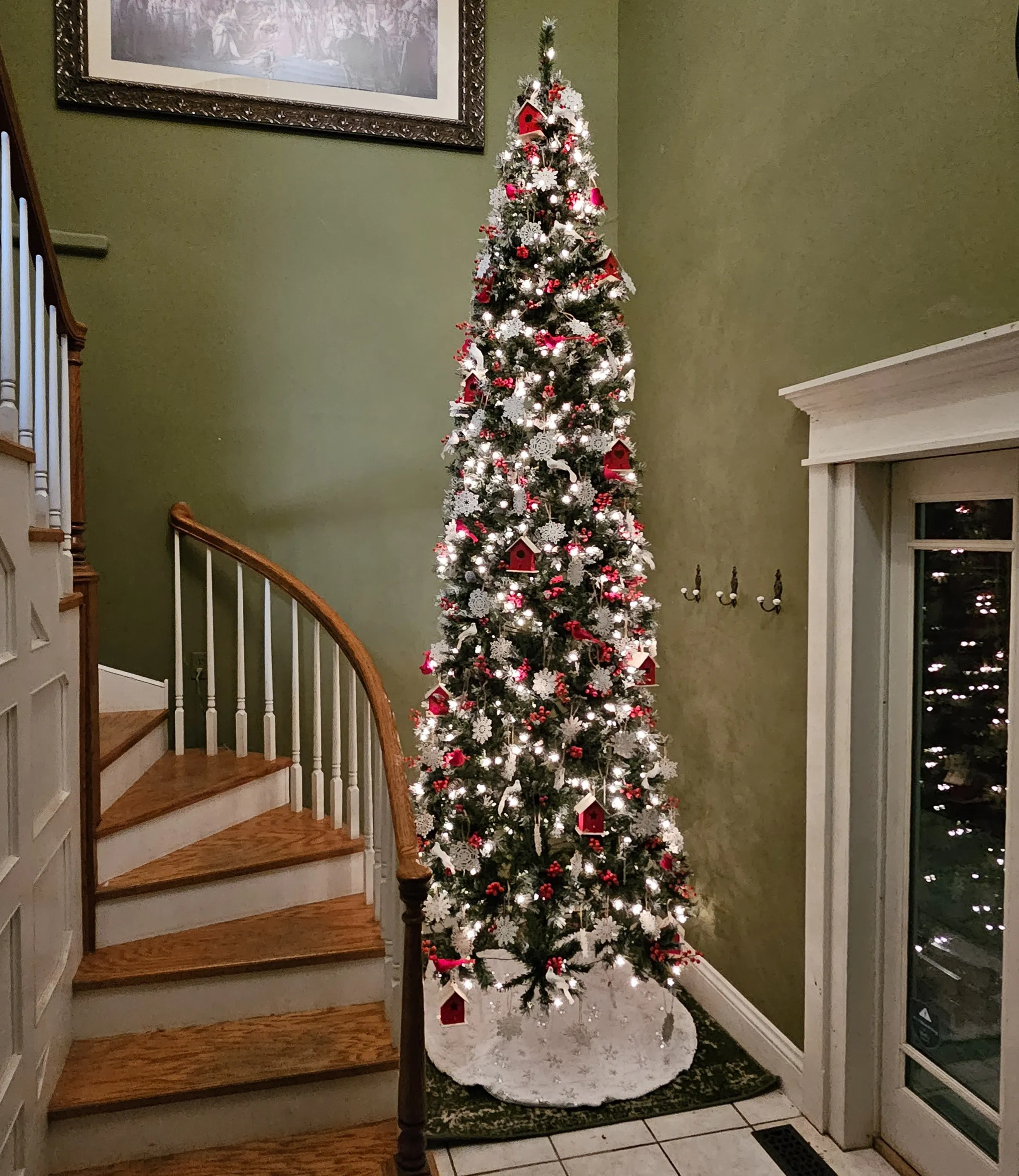 Slim 12- foot Christmas tree next to curved staircase