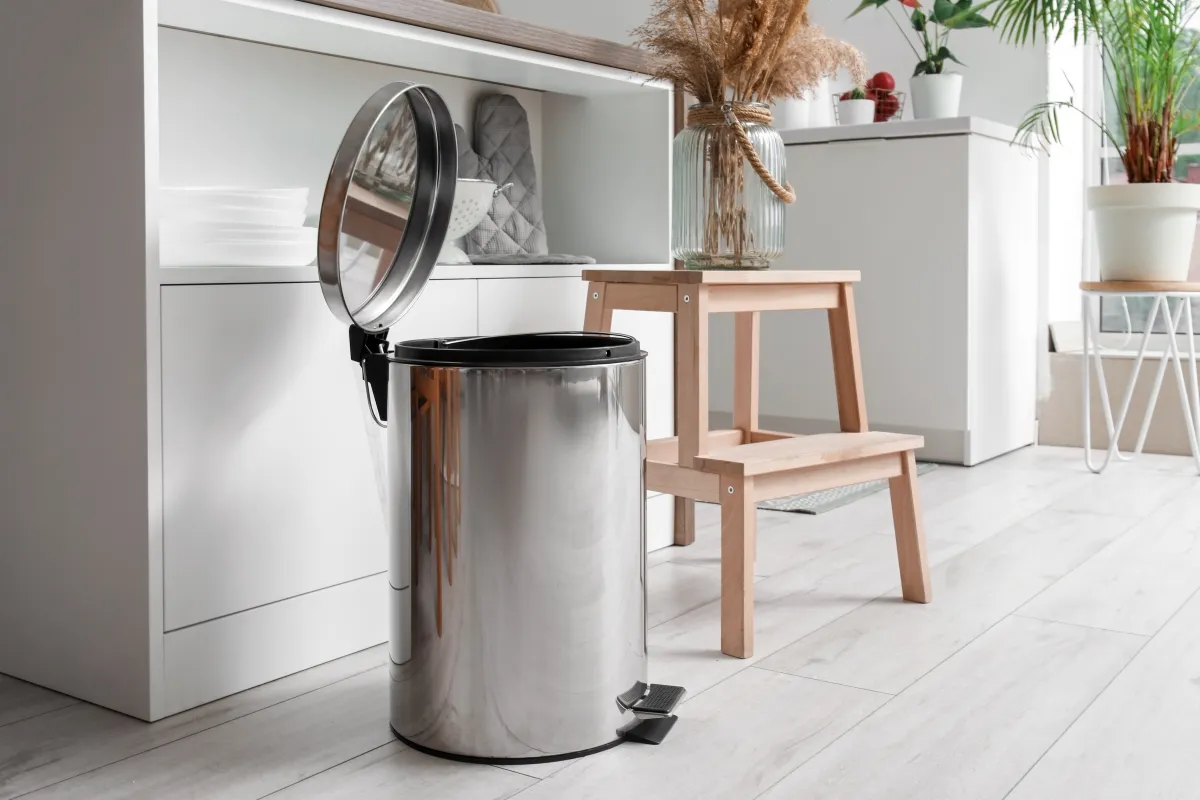 An opened metallic trash can in the kitchen.