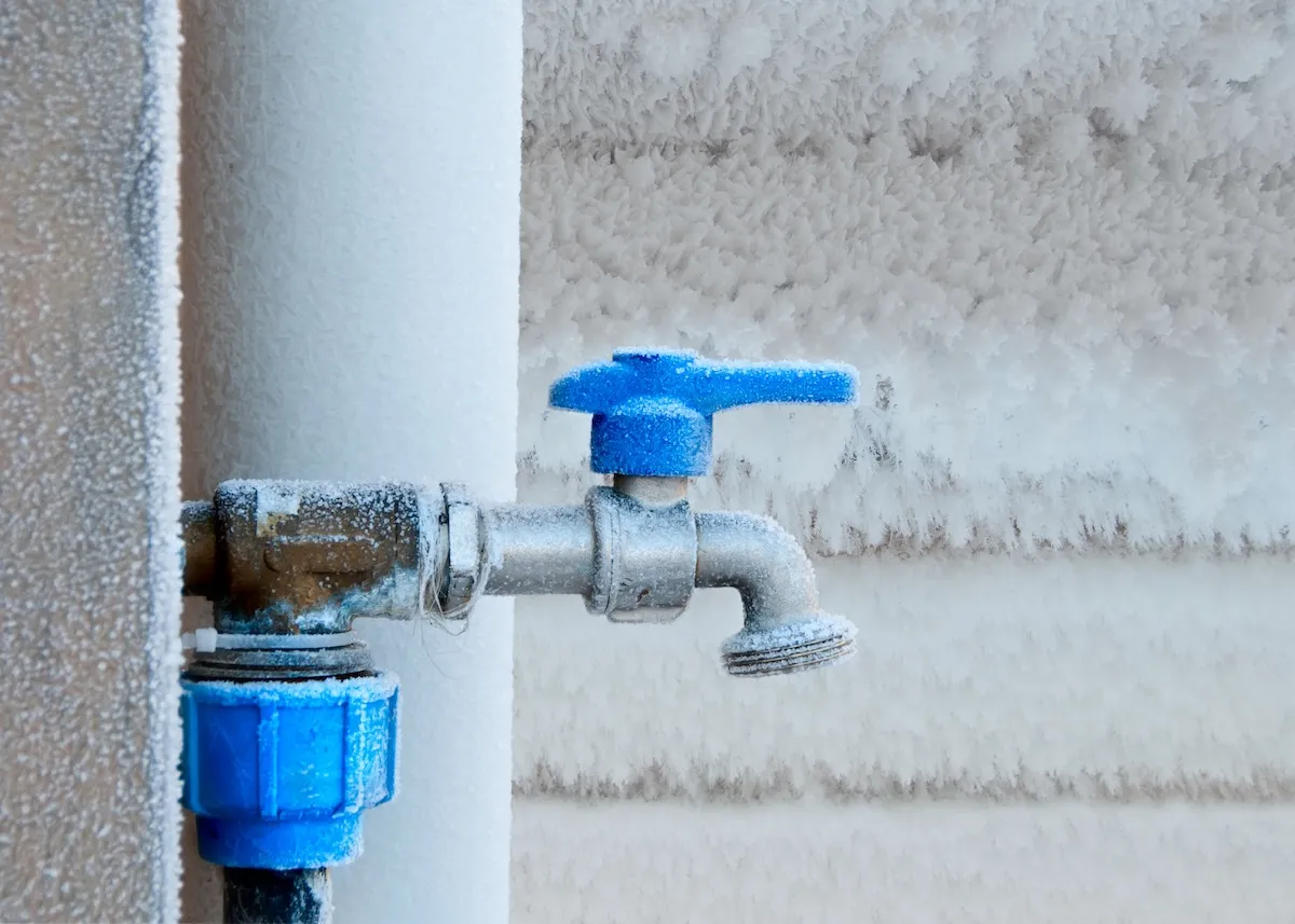 A frozen exterior water spigot collects ice and snow. 