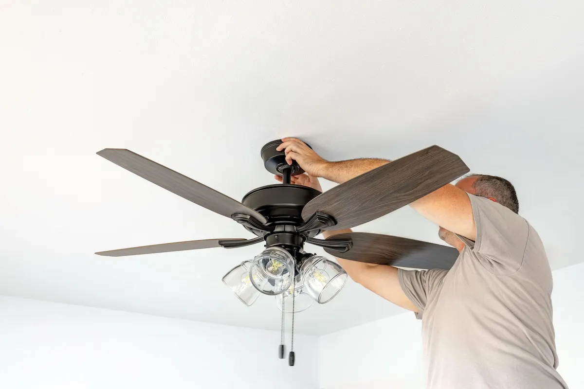 A man changes the direction of ceiling fans. 