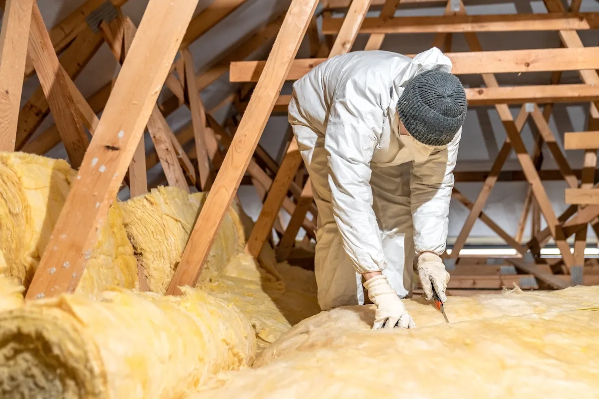 A professional insulation expert wears personal protective gear as he insulates a cold attic.
