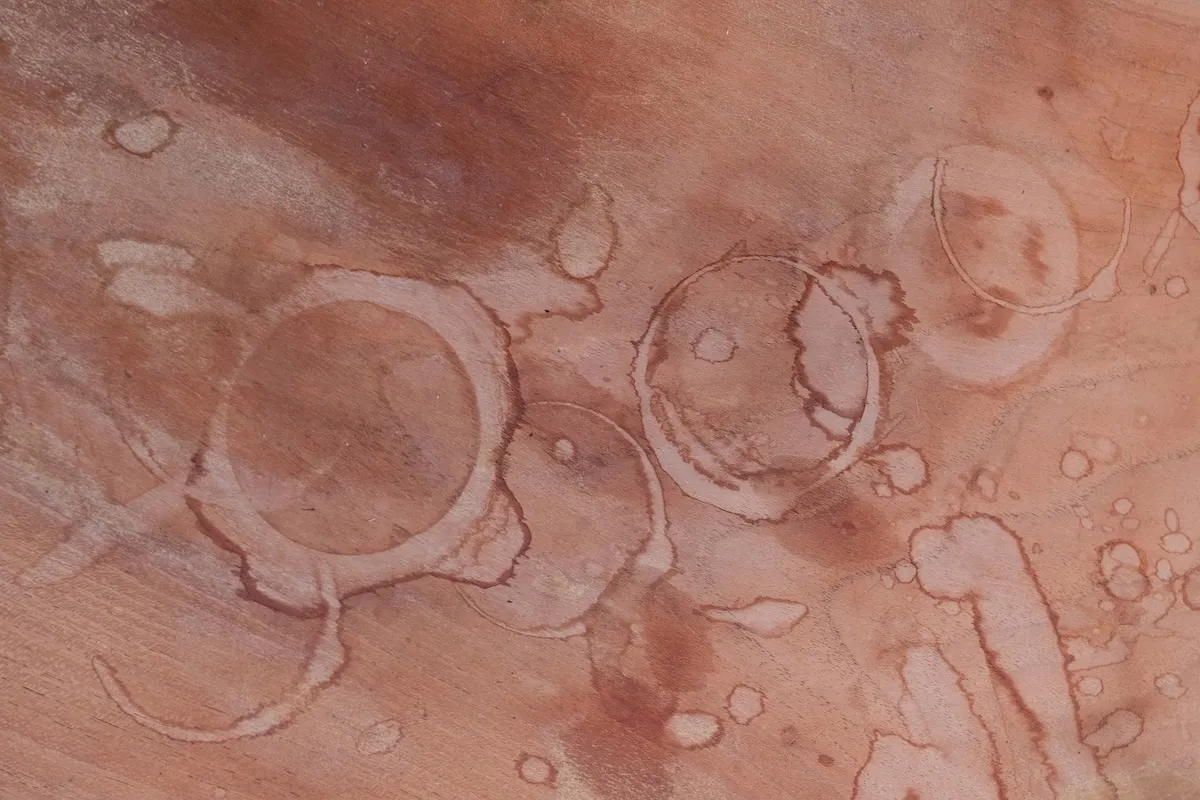 Round water stains, as from glassware, on a wood table.