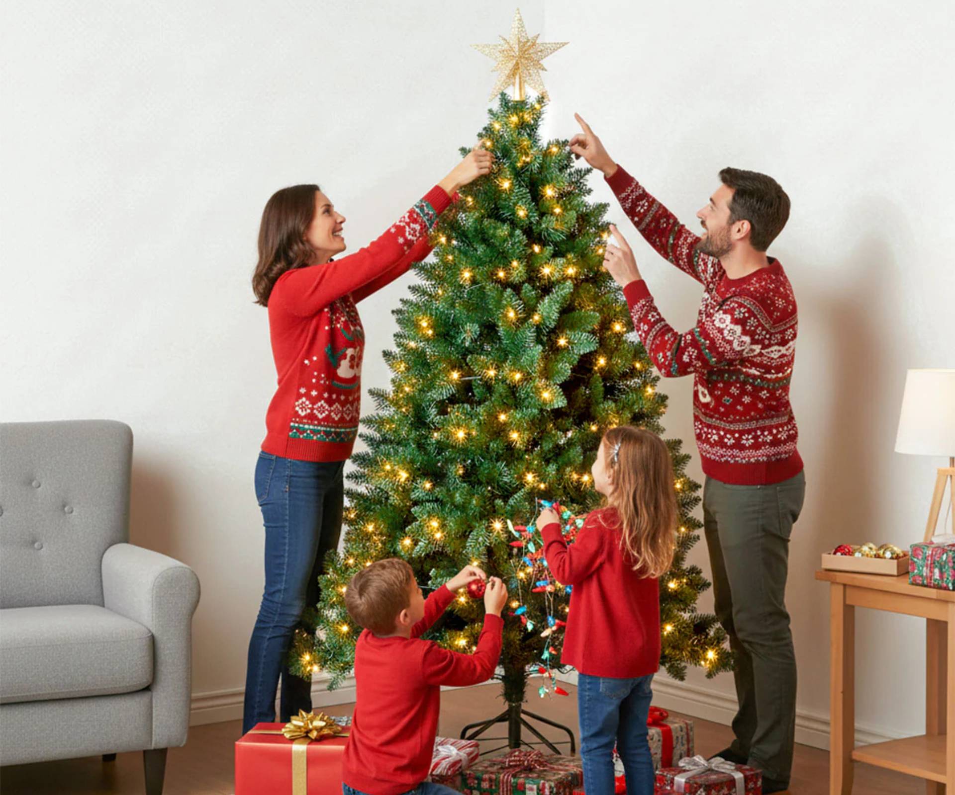 Une famille de quatre personnes décorant leur sapin de Noël artificiel pré-éclairé