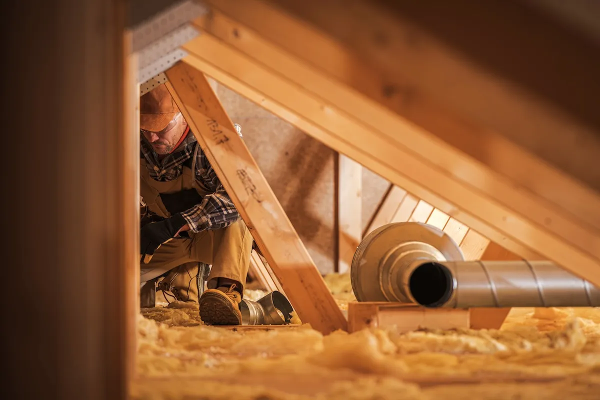 Worker among attic insulation and ventilation.
