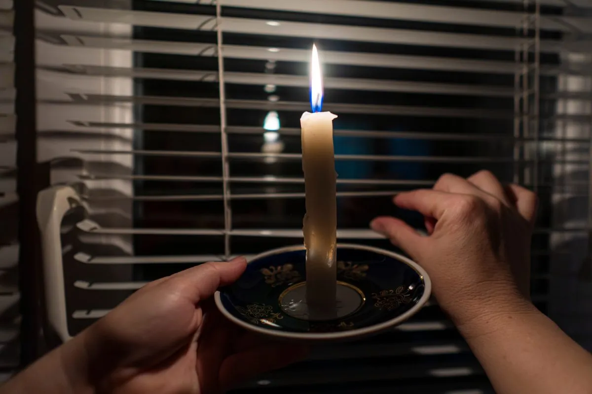 Hands holding a candle by a window